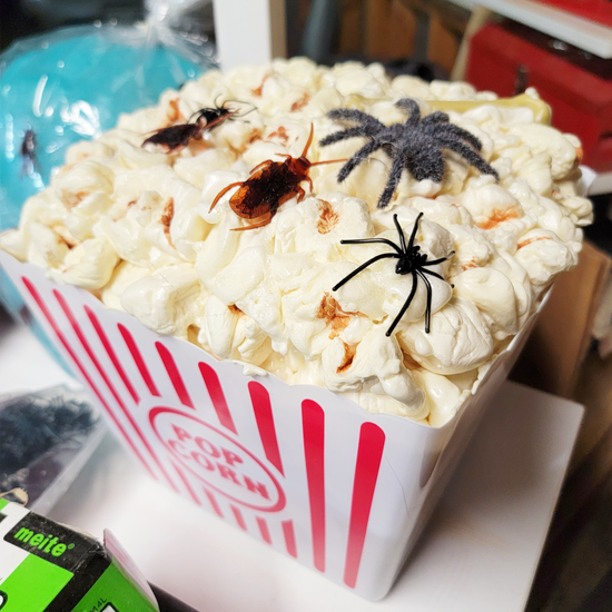 A tub of fake popcorn topped with fake spiders and cockroaches of various sizes.