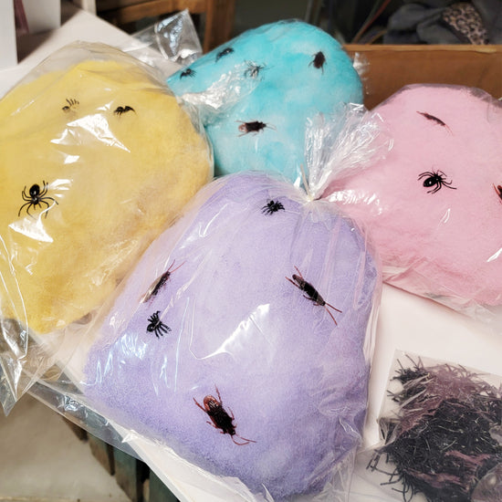 Bags of yellow, blue, purple, and pink cotton candy with plastic insect decorations on top.